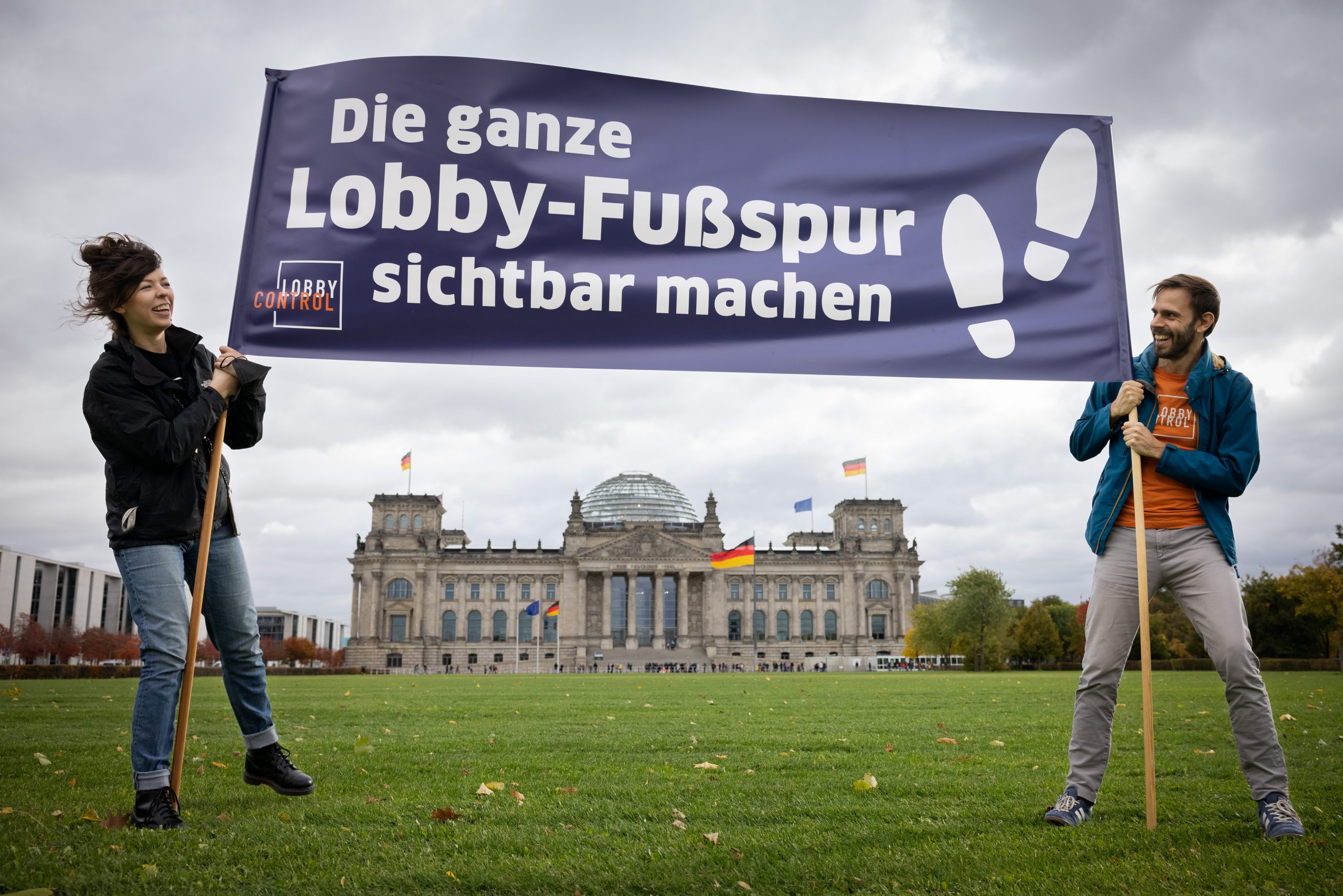 LobbyControl Team hält "Die ganze Lobby-Fußspur sichtbar machen" Banner vor dem Reichstag