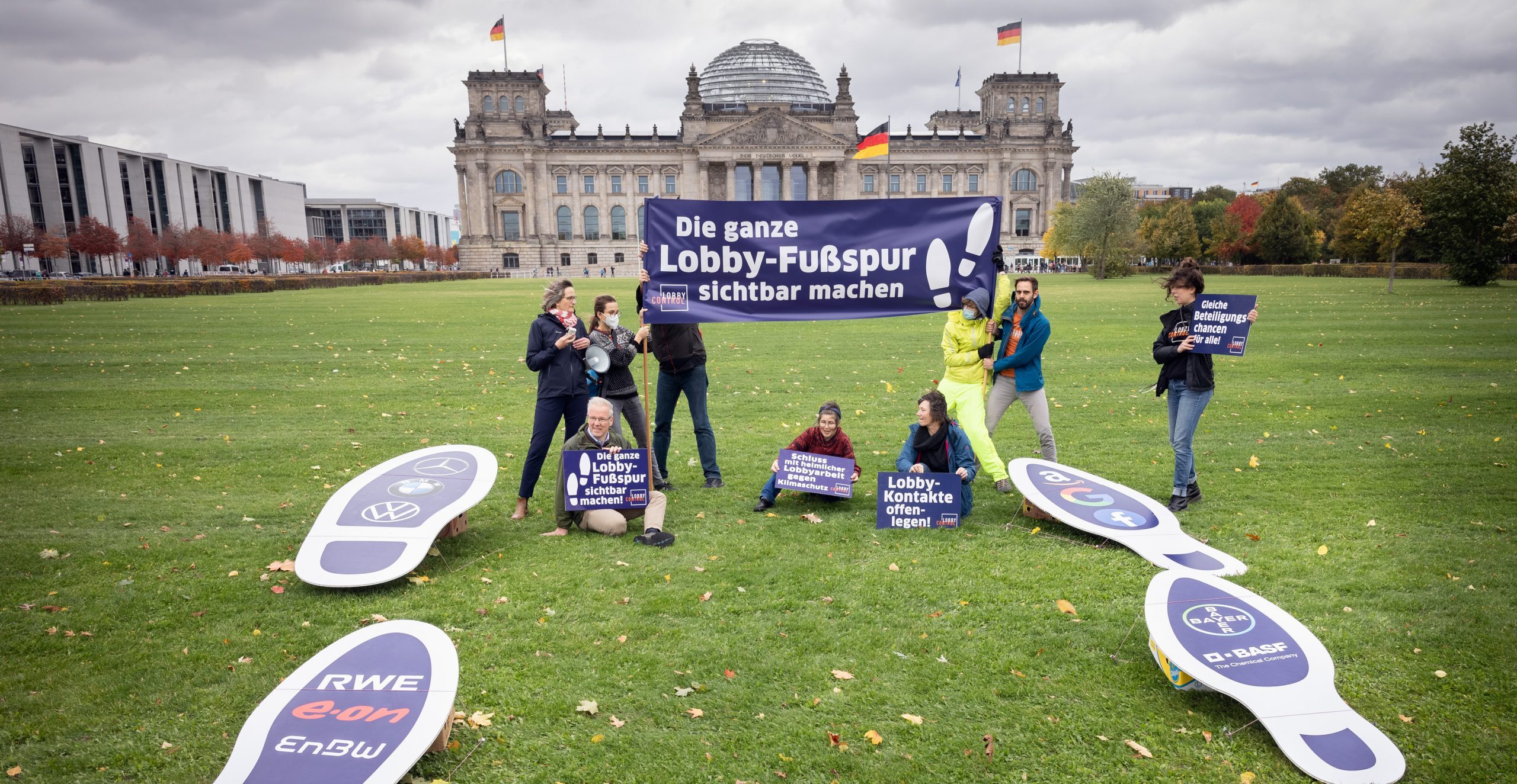 LobbyControl-Team mit "Die ganze Lobby-Fußspur sichtbar machen!" Schildern vor dem Bundestag