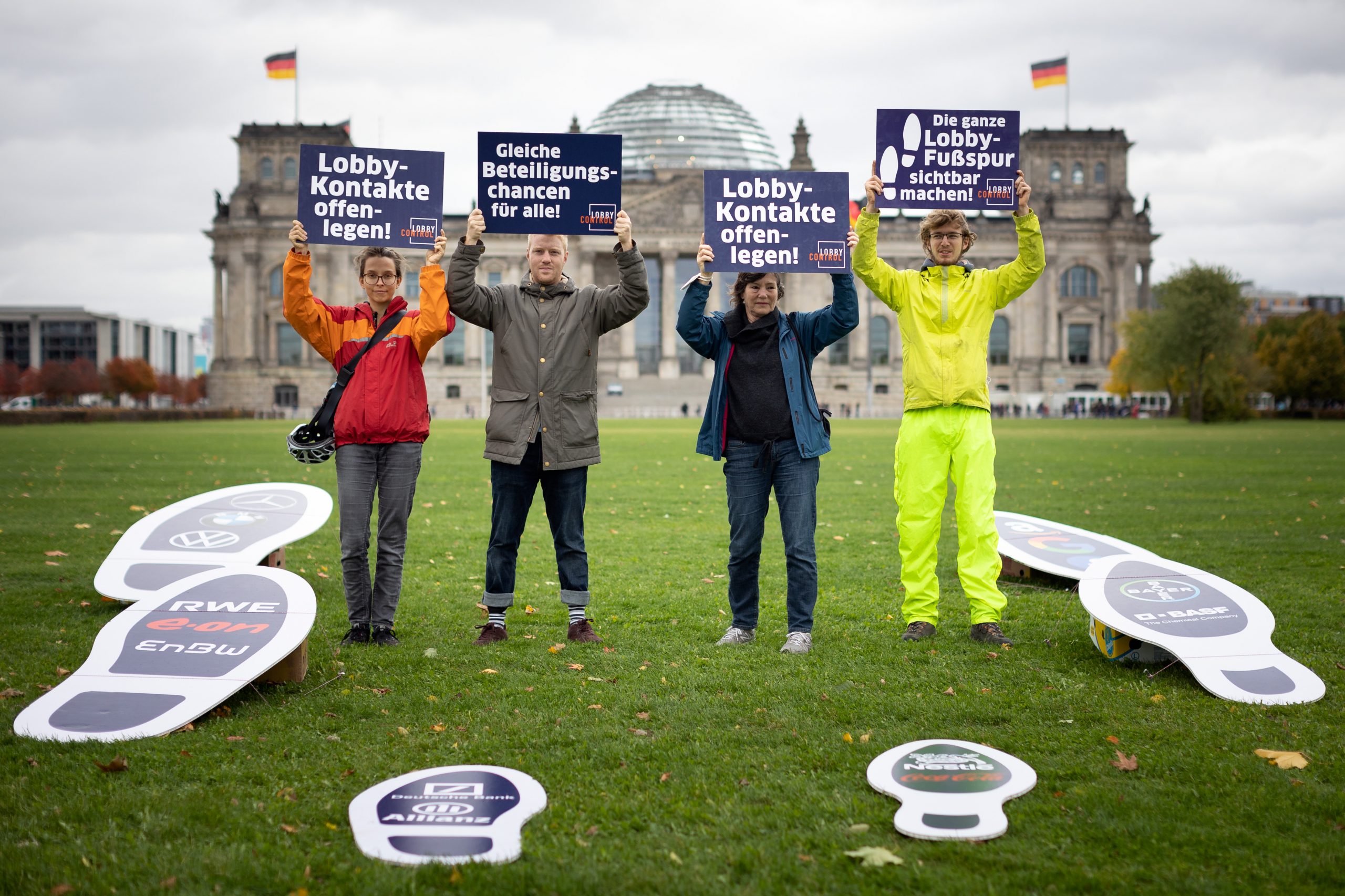 LobbyControl-Team mit "Die ganze Lobby-Fußspur sichtbar machen!" Schildern vor dem Bundestag