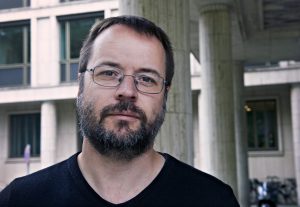 Porträt Johannes Kirsten, Mann mit Bart und Brille im scharzen T-Shirt